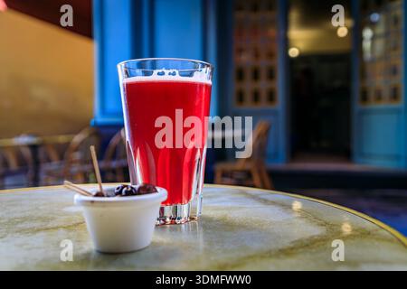 Ein Glas Himbeer-lambic-Bier in einem Restaurant im Freien mit verschwommenen Gebäuden in der Altstadt oder Vieille Ville in Nizza, Südfrankreich Stockfoto