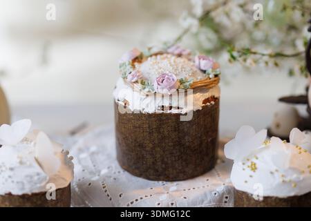 Osterkuchen und Eier auf Spitzentisch mit Frühlingsblütenzweigen, sanftes Tageslicht Stockfoto