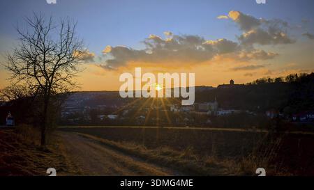 Ein idyllischer Sonnenuntergang über einer urbanen Landschaft mit einem Weg, der durch Felder führt, mit Blick in den Naturpark Kronach, Frankenwald Stockfoto