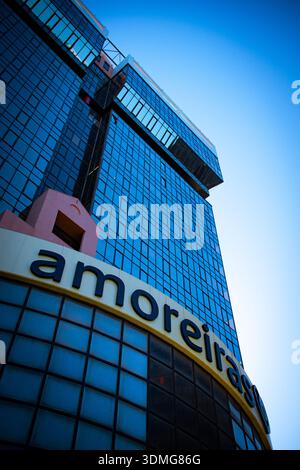 Flacher Blick auf einen modernen Glashochhaus im Amoreiras-Komplex in Lissabon, der den blauen Himmel reflektiert und die zeitgenössische Architektur betont Stockfoto