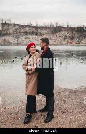 Ein Mann und eine Frau stehen am Valentinstag zusammen am Wasser. Sie teilen ein Lächeln, während sie ihre Zeit in der Natur genießen. Stockfoto