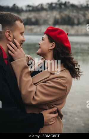 Zwei Personen teilen sich am Valentinstag einen freudigen Moment am Wasser. Sie sind eng beieinander, lächeln und glücklich, in einer natürlichen Umgebung. Stockfoto
