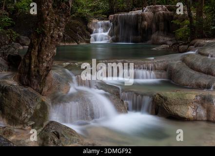 Wasserfälle im Erawan-Nationalpark, Thailand. Gestufte Wasserfälle fließen über Felsen. Üppig grüner Wald umgibt die malerische Landschaft. Stockfoto