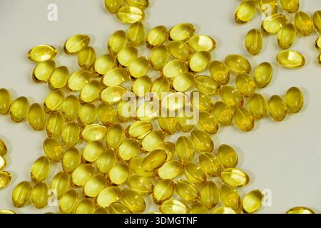 Gelbe Gelatinekapseln mit Omega 3, Fischöl, Vitamin D und Nahrungsergänzungsmittel auf weißem Hintergrund. Stockfoto
