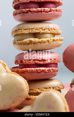 Verschiedene Arten von Makaronen sind in einem vertikalen Stapel angeordnet. Die Macarons sind in verschiedenen Farben erhältlich, darunter Pink, Orange und Creme. Stockfoto