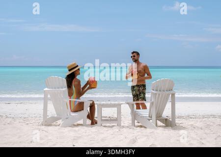 Ein Paar genießt einen ruhigen Moment am Grand Anse Beach in Praslin Seychellen. Umgeben von kristallklarem Wasser schlürfen sie tropische Cocktails während Baski Stockfoto