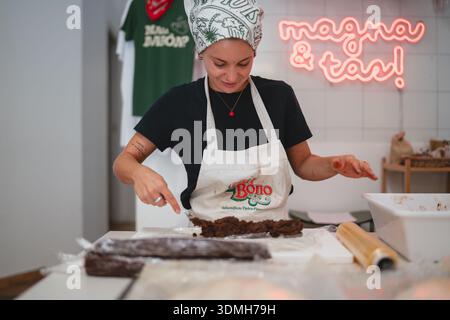 Piacenza, Italien - 30. August 2025 Küchenchefin bereitet Schokoladendessert in einer Küche mit Neonschild zu Stockfoto