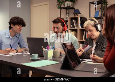 Eine Gruppe verschiedener junger Fachkräfte arbeitet während eines Teammeetings in einem modernen Startup-Büro an einem Projekt mit Laptops und digitalen Tablets zusammen Stockfoto