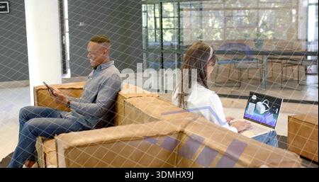 Rücken an Rücken auf braunem Sofa sitzen, Lounge, Mann grau, das Telefon überprüft, Frau weiß, die 3D-Laptop bearbeitet Stockfoto