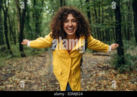 Junge Frau genießt die Natur im Wald unter dem Regen. Stockfoto