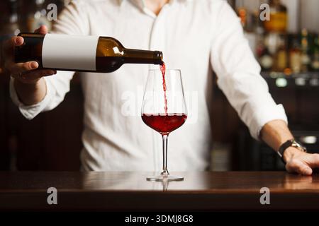 Sommeliermännchen gießt Rotwein in langstielige Weingläser. Stockfoto