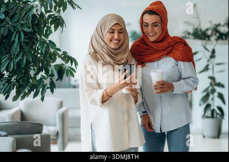 Stehen, tagsüber. Zwei Frauen sind drinnen in der modernen Halle des Gebäudes. Stockfoto