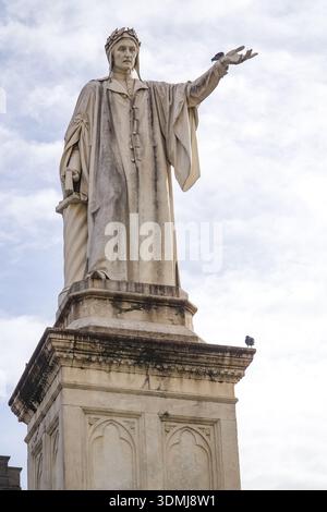 Statue von Dante Alighieri (Dante Alighieri) auf der Piazza Dante, Neapel, Kampanien, Italien. Historisches Denkmal zu Ehren des Dichters, vor bewölktem Himmel. Stockfoto