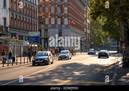 Dieses Bild zeigt eine geschäftige Straßenszene in der Nähe des historischen Grand Hotel Union, das den pulsierenden Stadtpuls von Ljubljana, Slowenien, einfängt. Autos fahren entlang Stockfoto