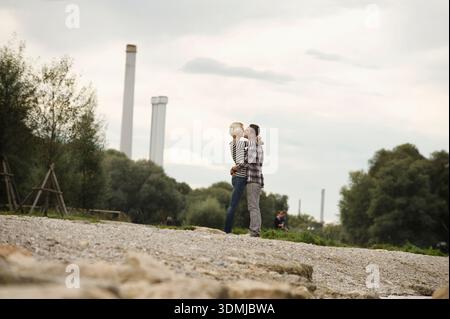 Romantisches Paar, das sich am Flussufer in der Stadt küsst und umarmt Stockfoto
