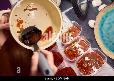 Suppen servieren. Zubereitung von einzelnen Portionen vibrierender Tomatenbrühe in Behältern. Durchsichtige Boxen vorsichtig mit reichhaltigem Gemüse und füllen Stockfoto