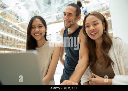 Verschiedene Freunde, die Spaß am Lachen und Arbeiten am Notebook haben Stockfoto