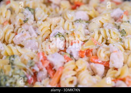 Herzhafter Rotini mit gemischtem Gemüse, serviert in einem großen Tablett im Familienstil. Gemütliche rustikale Rotini-Pasta mit Gemüse für Familien und Feiern Stockfoto