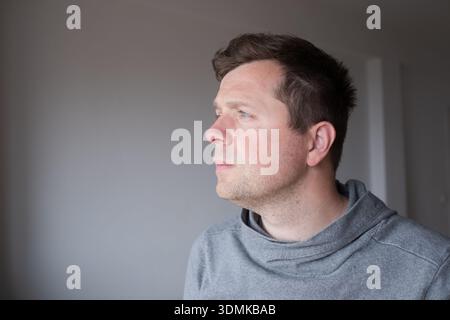 Nachdenklicher junger Mann mit beleuchtetem Gesicht, der wegschaut und von der Zukunft träumt Stockfoto