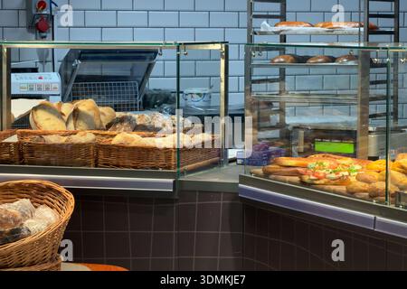 Die gut beleuchtete, moderne Bäckerei verfügt über Glasdisplays, die mit einer ansprechenden Auswahl an frisch gebackenem Brot, zubereiteten Sandwiches und Cottag gefüllt sind Stockfoto
