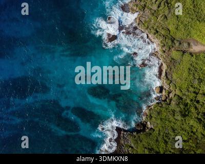 Blick aus der Vogelperspektive auf die zerklüftete Küste, wo türkisfarbenes Wasser auf die üppige grüne Vegetation trifft, Guam, USA. Stockfoto