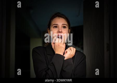 Die Frau in der Tür schreit vor Angst, ihr Gesicht zeigt intensive Überraschung und Schrecken und betont Emotionen von Schock und Angst. Die Frau hatte Angst vor dem Stockfoto