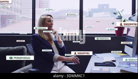 Sitzende reife Frau im marineblauen Blazer, aufliegendes Kinn, Maus am Schreibtisch mit Datenbeschriftungen Stockfoto
