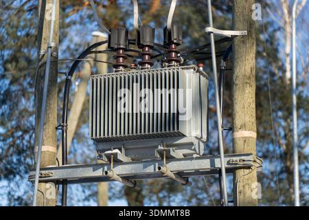 Detailansicht des elektrischen Transformatorkastens am Versorgungsmast, isolierte Steckverbinder und Verkabelung am Metallquerträger, Stromnetzgeräte bei Tageslicht Stockfoto