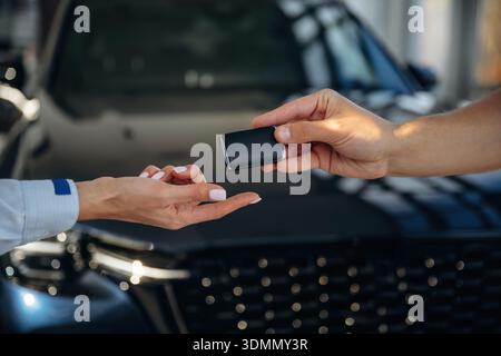 Nahaufnahme der Hände von Frauen und Männern, die die Schlüssel für ein neues Auto nehmen. Stockfoto