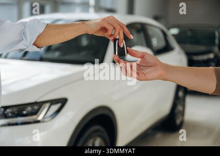 Nahaufnahme der Hände von Frauen und Männern, die die Schlüssel für ein neues Auto nehmen. Stockfoto
