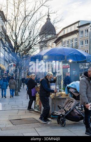 Händler Und Menschenmassen Genießen Warm Geröstete Kastanien. Lebhafte Nächtliche Marktszene Mit Saisonalen Spezialitäten Aus Gerösteten Nüssen Stockfoto