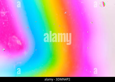Abstrakter Regenbogenhintergrund mit sanfter Unschärfe und winzigen Öltropfen. Gleichmäßige Übergänge zwischen rosa, blauen, grünen und orangen Farben Stockfoto