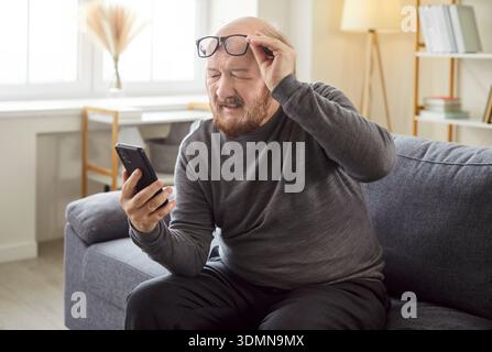Älterer Mann Mit Smartphone, Der Mit Dem Sehvermögen Kämpft Stockfoto