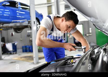 Kfz-Mechaniker in einer Werkstatt die Reparatur eines Fahrzeugs Stockfoto