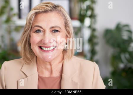 Selbstbewusste professionelle Frau lächelt in Beige Blazer – Büroporträt für Unternehmen und Führung Stockfoto