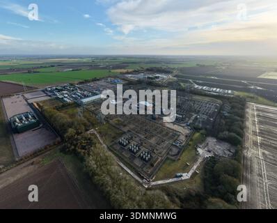 Aus der Vogelperspektive einer weitläufigen Walpole-Umspannstation National Grid unter hellem Himmel, im Kontrast zu den gedämpften Grün- und Brauntönen der umliegenden Landschaft Stockfoto