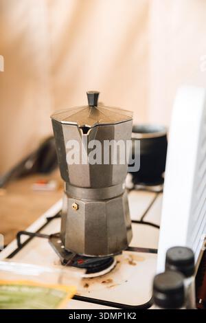 Moka-Topf, der Kaffee auf dem Campingofen in der Glamping-Zeltküche aufbrüht Stockfoto