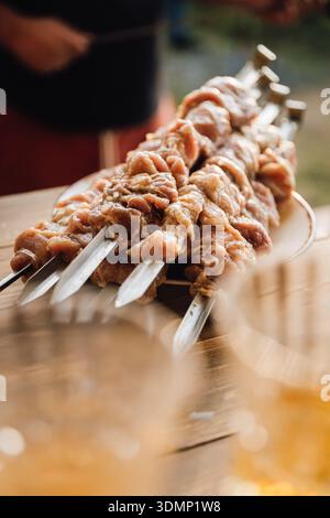 Rohes mariniertes Fleisch auf Metallspießen auf Holztisch, Grillzubereitung aus der Nähe Stockfoto