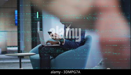 Arbeitender Mann im Anzug, der auf einem Laptop im blauen Klubsessel schreibt, Smartphone hält, blaublauer Punkt-Trennwand Stockfoto