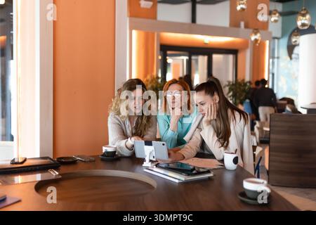 Geschäftsfrauen arbeiten während der Besprechungszeiten am Nachmittag in einer modernen Büroumgebung auf mobilen Geräten zusammen Stockfoto
