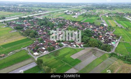 Eine ländliche Gegend mit einem kleinen Dorf in der Mitte. Das Dorf ist von grünen Grasfeldern umgeben Stockfoto