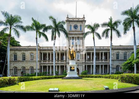 Die Bronzestatue von König Kamehameha I. steht vor dem historischen Gebäude Aliʻiōlani Hale, einem wichtigen Wahrzeichen und Sitz des höchsten Hofes des Staates. Stockfoto