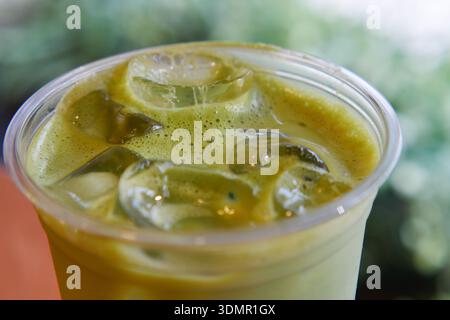Matcha-Getränk mit Eis in klarer Tasse auf Holztisch Stockfoto