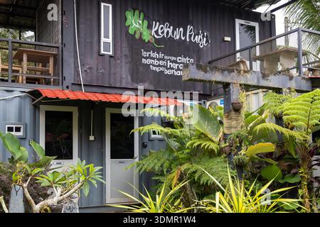 Außenaufnahme eines modernen zweistöckigen, modularen Homestay aus umgenutzten Containern, mit der markanten Beschilderung „Kebun Pagi“. Stockfoto