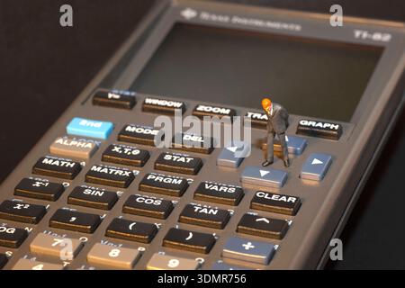 Miniatur-Geschäftsmann, der auf Taschenrechnertasten steht und als konzeptionelle redaktionelle Illustration verwendet wird Stockfoto
