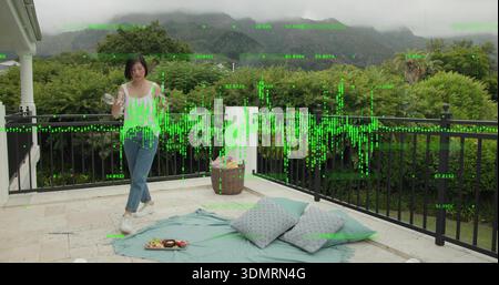 Stehende Frau in weißem Oberteil und Jeans, die Glas auf gefliester Terrasse hält, digitale Überlagerung, Kopierraum Stockfoto