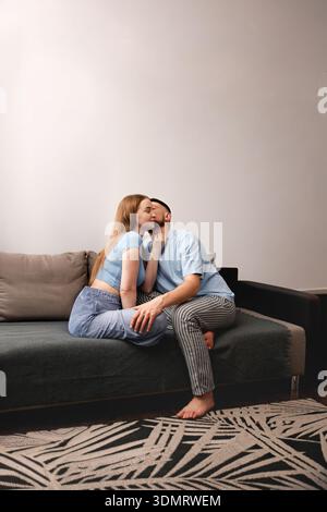 Romantisches Paar, das einen zärtlichen Moment auf einem gemütlichen Sofa in einem stilvollen Wohnzimmer genießt und Liebe und Zuneigung in einer modernen Wohnumgebung unterstreicht Stockfoto