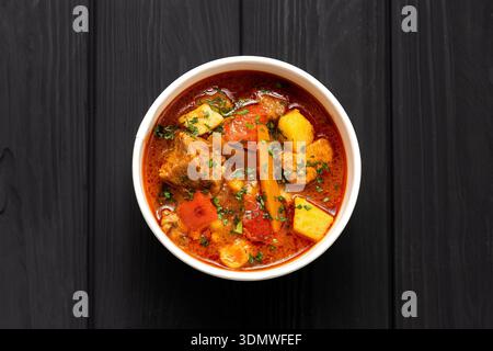 Ungarische Bohr-Gulasch-Suppe mit Rindfleisch und Gemüse in Kraftschale auf dunklem Holztisch Stockfoto