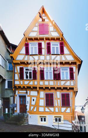 Schiefes gelbes Fachwerkhaus mit roten Fensterläden in der Altstadt von Tubingen Stockfoto
