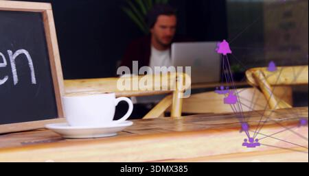 Arbeitender Erwachsener, der im Café auf silbernem Laptop tippt, dunkle Mütze und kastanienbraune Strickjacke trägt Stockfoto